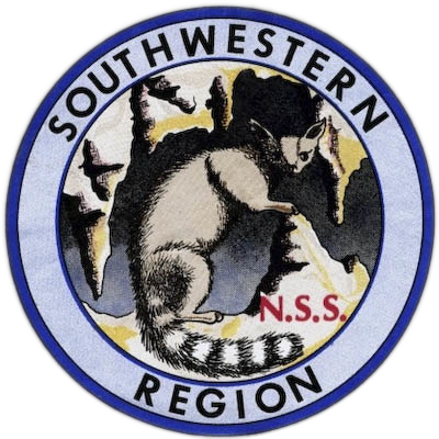 The logo of the Southwestern Region of the NSS, showing a ringtail in the entrance of a cave, looking toward the viewer. The cave around the ringtail has formations including stalagmites and stalactites.